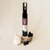 ail et olives 2 Bouteille de vinaigre balsamique ail et olive noire posée sur des rondins de bois, accompagnée d’une gousse d’ail et de plusieurs olives noires