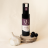 ail et olives 5 Bouteille de vinaigre balsamique ail et olive noire posée sur des rondins de bois, accompagnée d’une gousse d’ail et de plusieurs olives noires