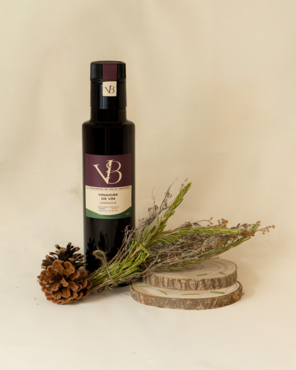 garrigue Bouteille de vinaigre de vin Garrigue de la Vinaigrerie de Haute-Provence, accompagnée de branches d’herbes de Provence et de pommes de pin