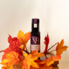 Bouteille de vinaigre de vin vendange tardive entourée de feuilles d’automne rouges et orangées