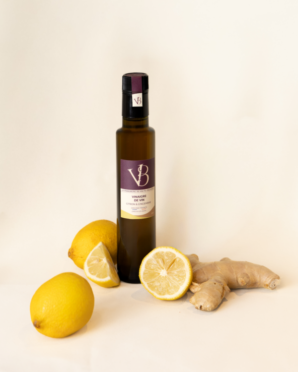 citron gingembre 2 Bouteille de vinaigre au citron et gingembre entourée de citrons frais et de racines de gingembre sur fond clair