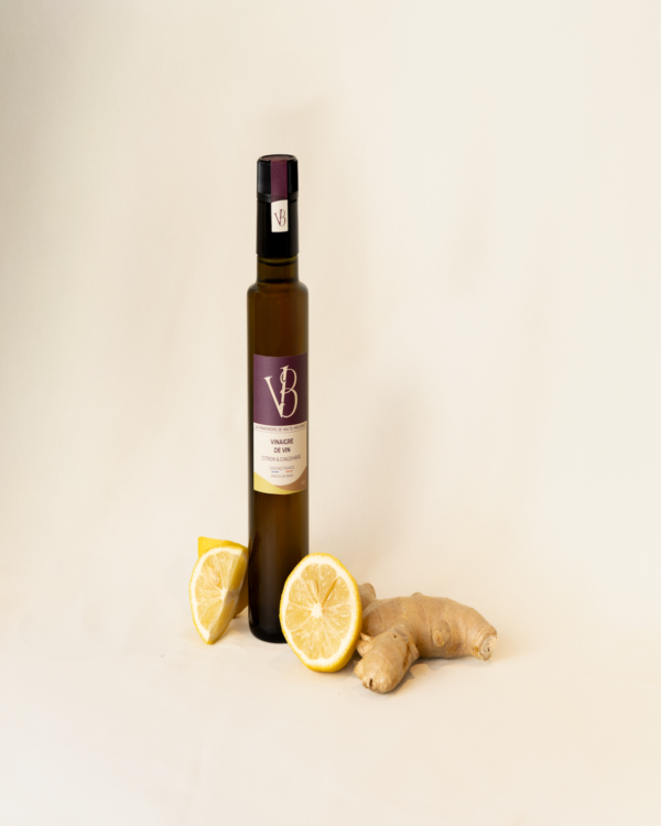 citron gingembre 3 Bouteille de vinaigre au citron et gingembre entourée de citrons frais et de racines de gingembre sur fond clair
