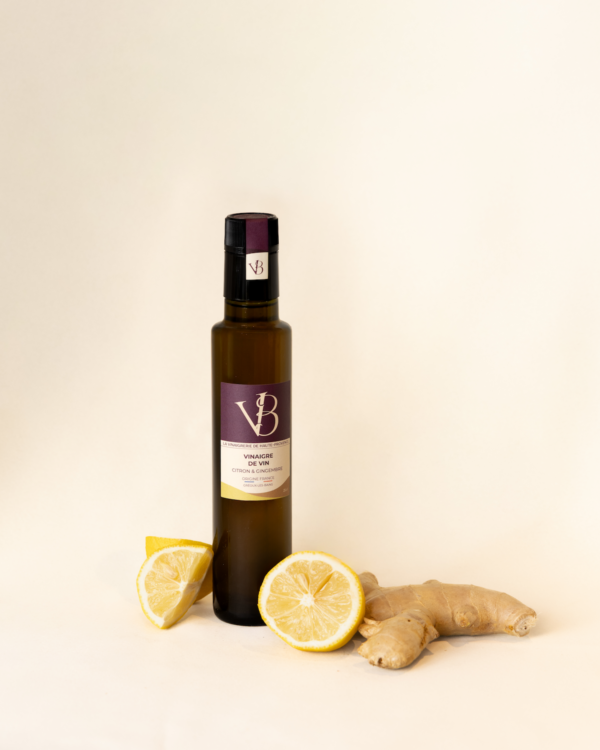 citron gingembre 4 Bouteille de vinaigre au citron et gingembre entourée de citrons frais et de racines de gingembre sur fond clair