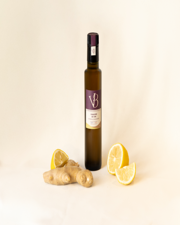 citron gingembre 5 Bouteille de vinaigre au citron et gingembre entourée de citrons frais et de racines de gingembre sur fond clair