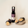 Bouteille de vinaigre balsamique à la figue entourée de figues fraîches coupées, posées sur des rondins de bois