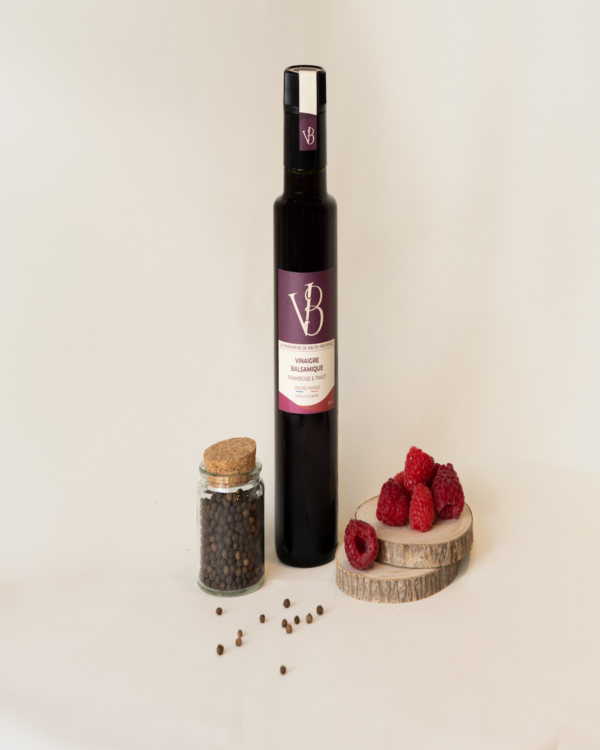 framboise Bouteille de vinaigre balsamique framboise & timut entourée de framboises fraîches et d’un pot de poivre