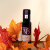 Bouteille de vinaigre de vin vendange tardive entourée de feuilles d’automne rouges et orangées
