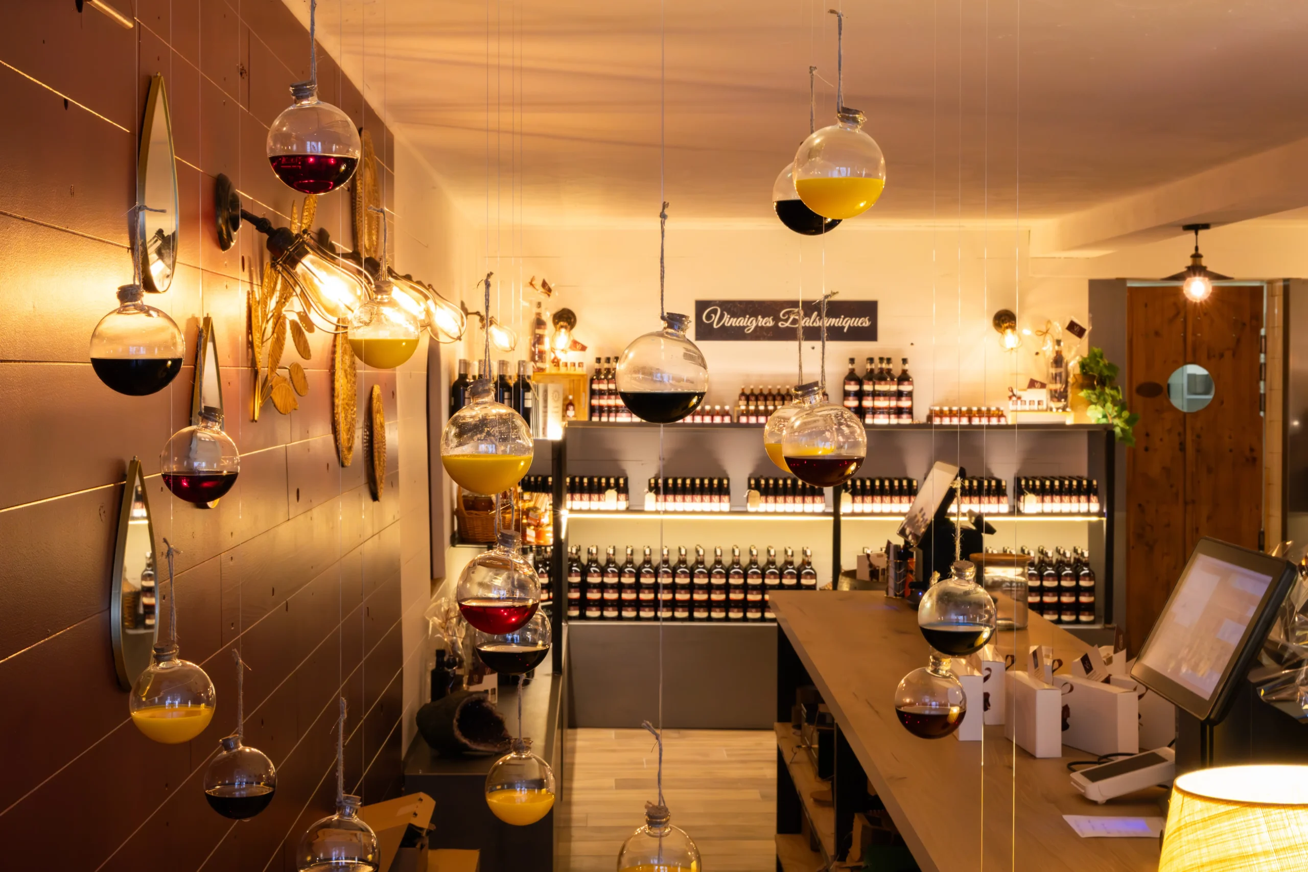 Intérieur chaleureux de la boutique de la Vinaigrerie de Haute-Provence, avec suspensions décoratives remplies de vinaigre et étagères de produits artisanaux en arrière-plan