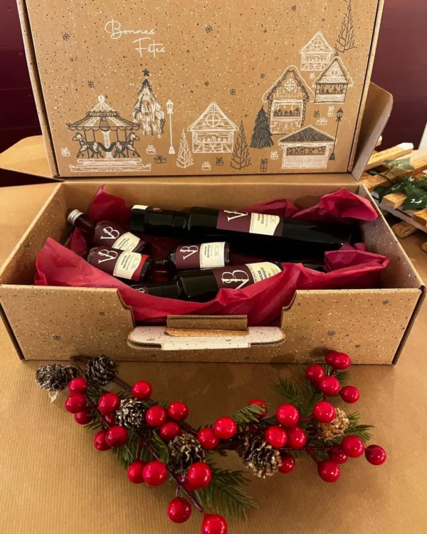 Coffret cadeau de Noël artisanal contenant plusieurs bouteilles de vinaigre et balsamique VB, présentées dans un emballage festif décoré de motifs hivernaux.