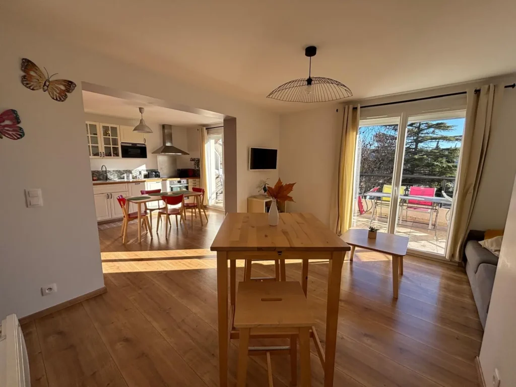 Séjour lumineux avec salle à manger, cuisine ouverte et accès à la terrasse dans l’appartement La Vigne à Gréoux-les-Bains.